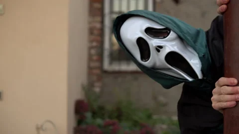 A man in a screaming mask appears from around the corner of the opening and Stock Footage 163777976