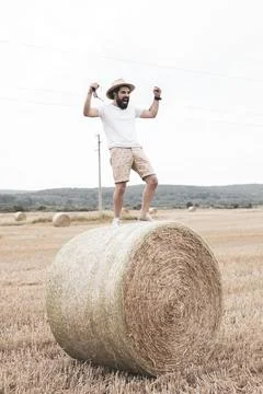 Man screaming while standing on a round bale of dry straw. Stock Photos