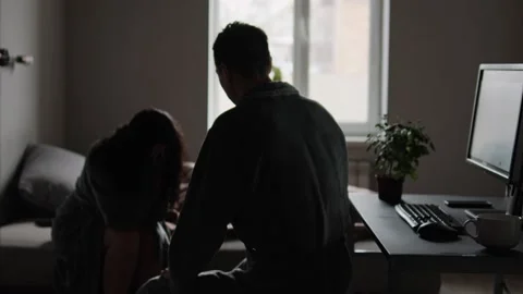 Man screams and gestures at crying woman in dim bedroom. Domestic violence and Stock Footage 307613779