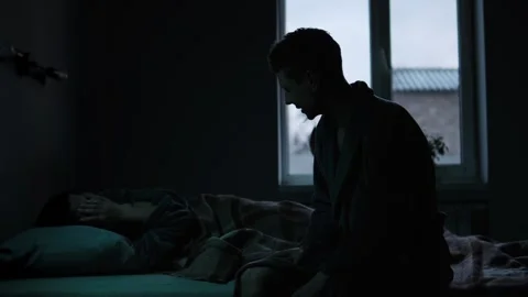 Man screams and gestures at crying woman in dim bedroom. Domestic violence and Video stock 307614330