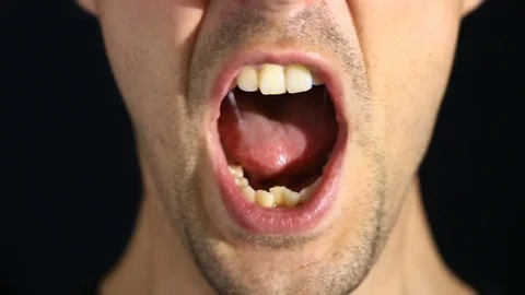 Man screams into the camera on a black background. Mouth and grin close-up Stock Footage 75753575