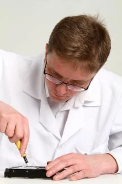 A man with a screwdriver disassembles a computer hard drive repair Stock Photos