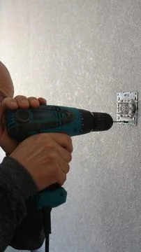 A man with a screwdriver is fixing light switch Stock Photos