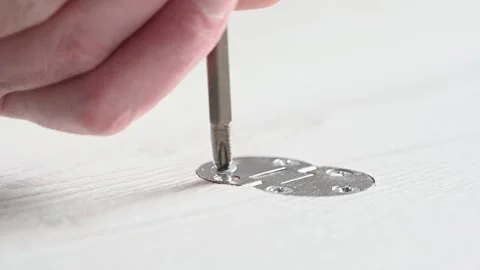 A man with a screwdriver in his hands is screwing a screw into the door hinge Stock Footage 290043545