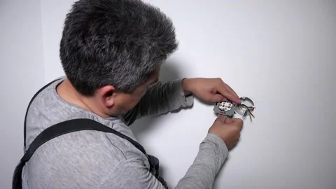 Man with screwdriver screw electrical outlet on wall Video stock 132420282