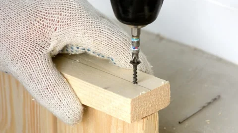 Man screwing boards using electric screwdriver. Assembling wooden rack on floor  Stock Footage 130439289