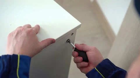 A man screwing a countersunk screw with a screwdriver, assembling a cabinet Stock Footage 202302880