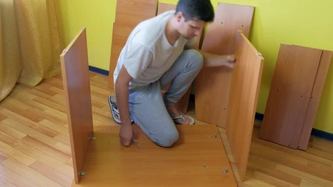 Man screwing parts of table joining them together with iron corners and bolts. Video stock 124857552