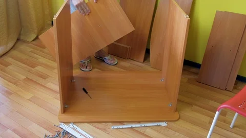 Man screwing parts of table joining them together with metal corners and bolts. Stock Footage 124894457
