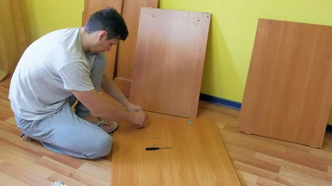 Man screwing parts of table joining them together with iron corners and bolts. Stock Footage 129418225