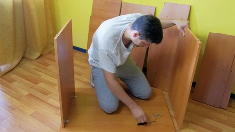 Man screwing parts of table joining them together with iron corners and bolts. Stock Footage 129418312