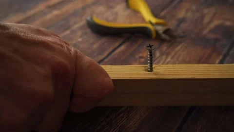 Man screwing a self-tapping screw into a wooden rail with a screwdriver Stock Footage 142342953