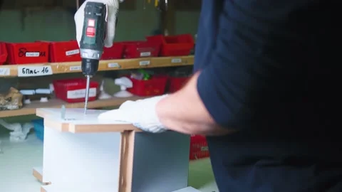 Man screwing a self-tapping screw into a chipboard with a screwdriver green Видео 231799600