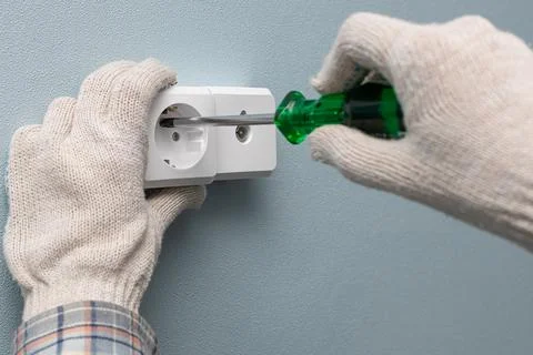 A man screwing a wall electrical socket with a screwdriver Stock Photos