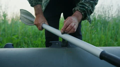 A man screws oars to an inflatable boat before morning fishing Stock Footage 237362708