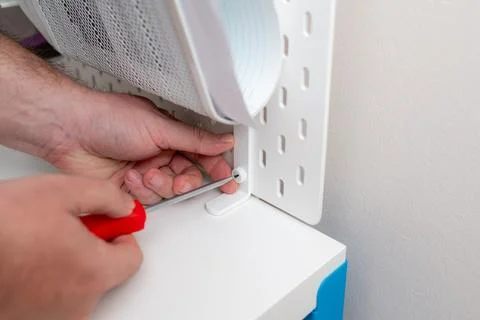 Man screws pegboard on white work table with screwdriver Stock Photos