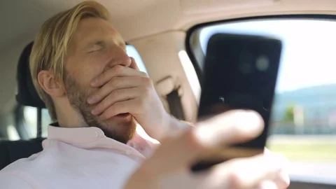 Man scrolling and checking smartphone while in a car and yawns Stock Footage 82826379