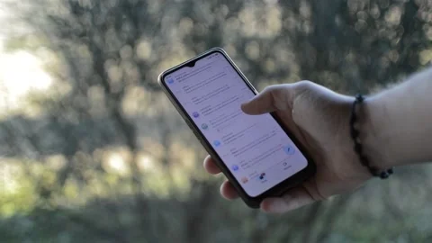 Man scrolling e mail on his smartphone, mobile communication in the garden Vidéo 170540020