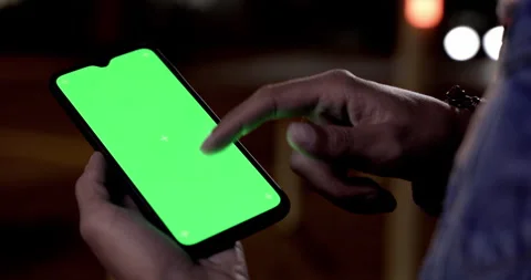Man scrolling on green screen mobile phone outdoors at night Stock Footage 147362708