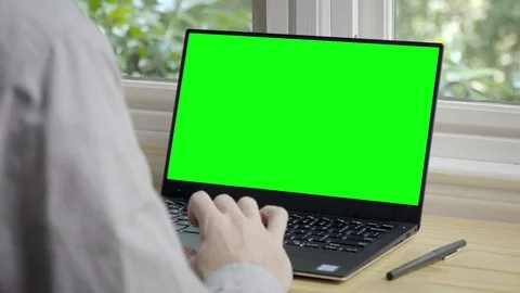Man Scrolling on Laptop at Window Desk Greenscreen Chroma Stock Footage
