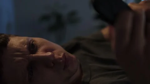 Man scrolling on phone in bed at night, unable to sleep. Close-up Stock Footage 296218312