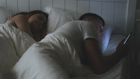 The man scrolling the smartphone screen, while his girlfriend is sleeping Stock Footage 146872719