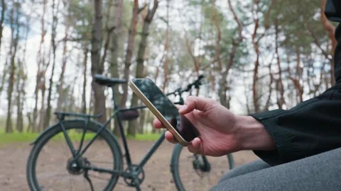 Man Scrolling on Smartphone While Resting with Bicycle in Forest Video stock 333824264