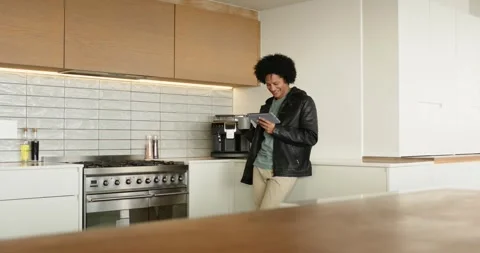 Man scrolling tablet in kitchen spotting coffee maker grabbing mug and sipping Stock Footage 342492612
