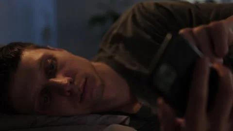 Man scrolling through phone in bed at night, struggling with sleeplessness and o Vídeo Stock 296423473