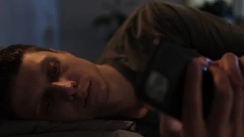 Man scrolls through his phone at night in bed, losing sleep due to social media  Stock Footage 296218159