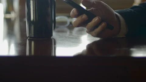 Man scrolls through his smart phone while in a coffee house at night Stock Footage 65338815