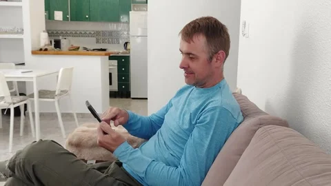 A man scrolls through the screen of a mobile phone in search of goods while Stock Footage 276916272
