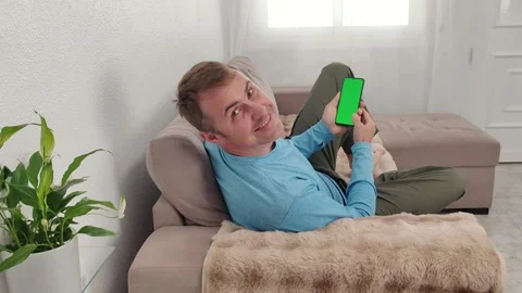A man scrolls through the screen of a mobile phone with a green chroma key Stock Footage 276919262