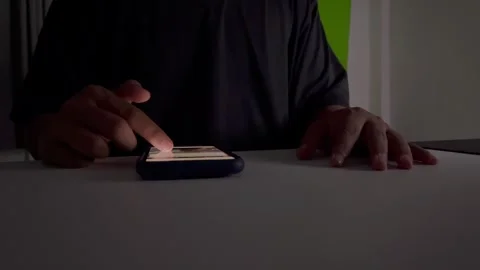 A man scrolls through social media on his smartphone at night Video stock 325041707