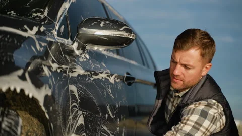 Man Scrubbing Car Side with Sponge at Outdoor Car Wash Stock Footage 297128204