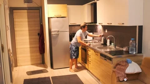 Man scrubbing kitchen backsplash with sponge and detergent, removing grease and Stock Footage 333578556