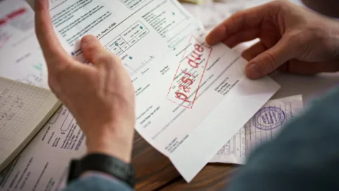 A man scrutinizes a receipt pulled from an envelope marked overdue against a Stock Footage 336570411