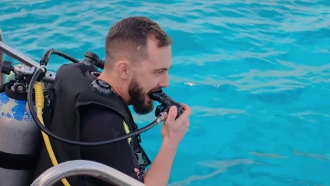 A man with scuba diving is sitting on board a yacht, preparing to dive, diving i Stock Footage 241238537