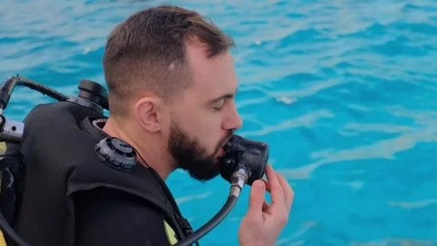 A man with scuba diving is sitting on board a yacht, preparing to dive, diving i Stock Footage 241238539