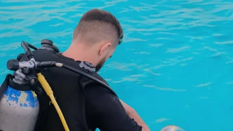 A man with scuba diving is sitting on board a yacht, preparing to dive, diving i Stock Footage 241238568