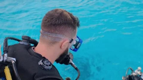 A man with scuba diving is sitting on board a yacht, preparing to dive, diving i Stock Footage 241238574