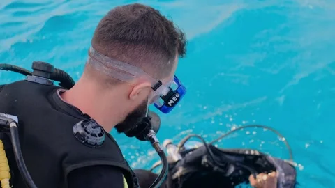 A man with scuba diving is sitting on board a yacht, preparing to dive, diving i Stock Footage 241238575