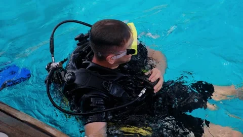 A man with scuba diving is sitting on board a yacht, preparing to dive, diving i Stock Footage 241238640