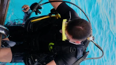 A man with scuba diving is sitting on board a yacht, preparing to dive, diving i Stock Footage 241238655