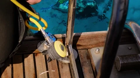 A man with scuba diving is sitting on board a yacht, preparing to dive, diving i Stock Footage 241238702