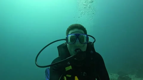 A man scuba diving swims deep with a selfie stick Vidéo 313077210