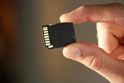 Man with SD memory card on blurred background, closeup Stock Photos