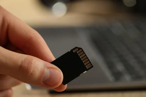 Man with SD memory card on blurred background, closeup. Space for text Stock Photos