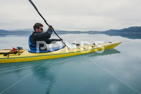 Man sea kayaking inan inlet on the Alaska coastline. Stock Photos