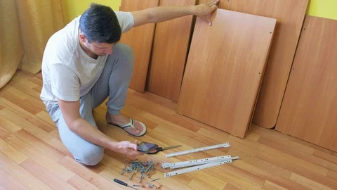 Man is searching in internet on smartphone how to collect the table from parts. Video stock 129417882